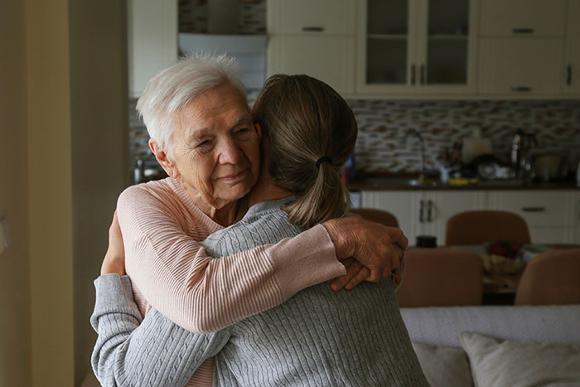 older lady hugging younger lady in kitchen