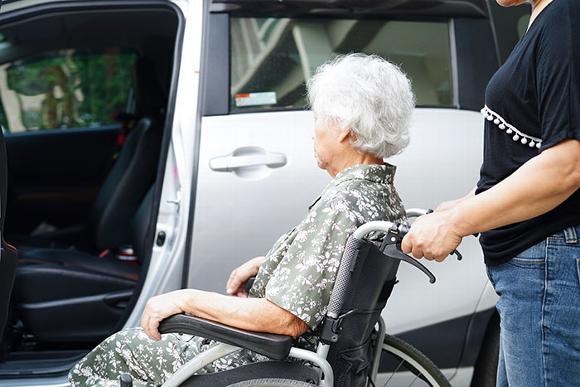elderly lady in wheel chair being pushed up to open car door