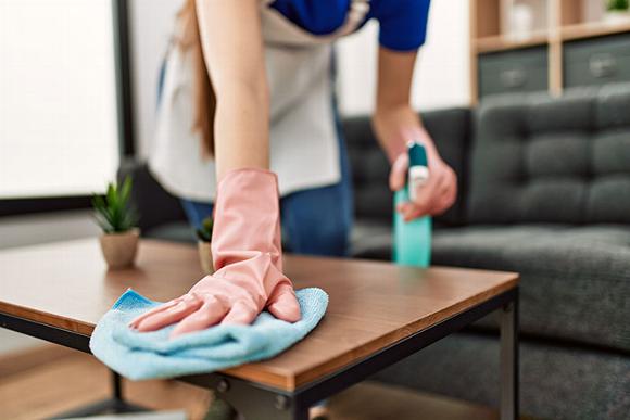 hand in rubber glove with cleaning cloth on coffee table