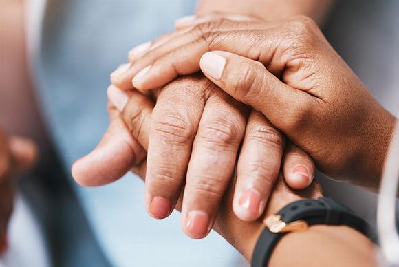 younger hand holding elderly persons hand